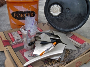 car parts, hypodermic needle, cigarette butts, bucket, and other trash
